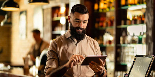 Homme utilisant une tablette connectée à une caisse enregistreuse pas chère dans un bar
